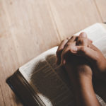 Spirituality and religion, Hands folded in prayer on a Holy Bible in church concept for faith.